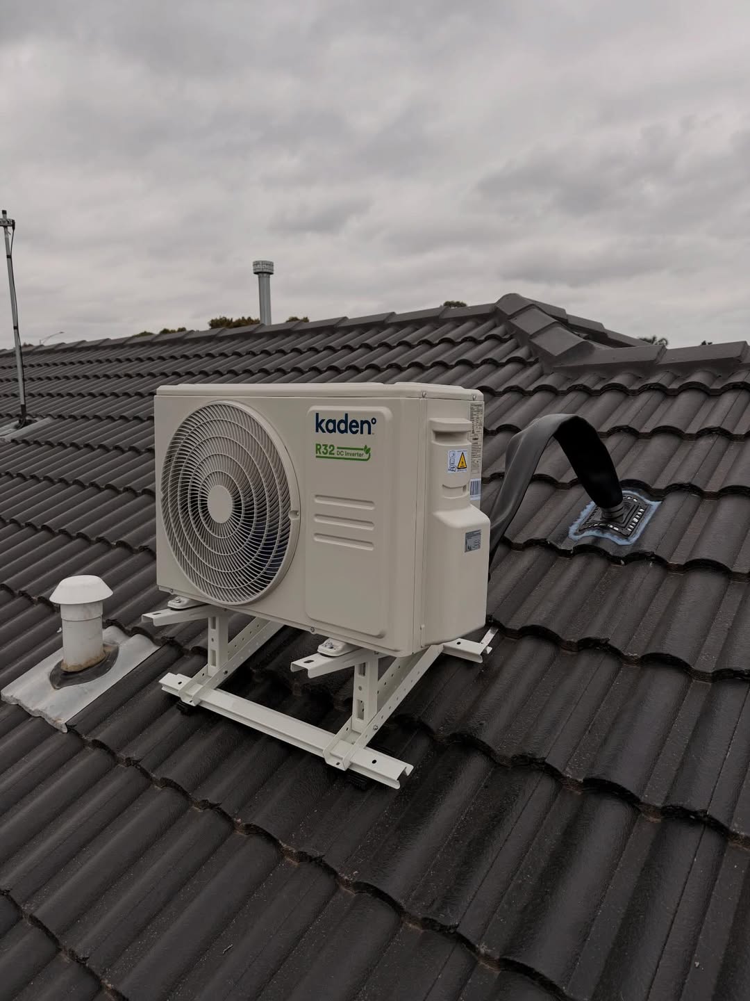 Kaden outdoor condenser mounted on a bracket outside a home